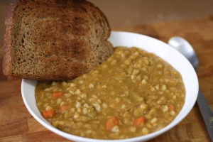 A photo of my Pea and Barley soup in a white bowl with some crusty wholemeal toast